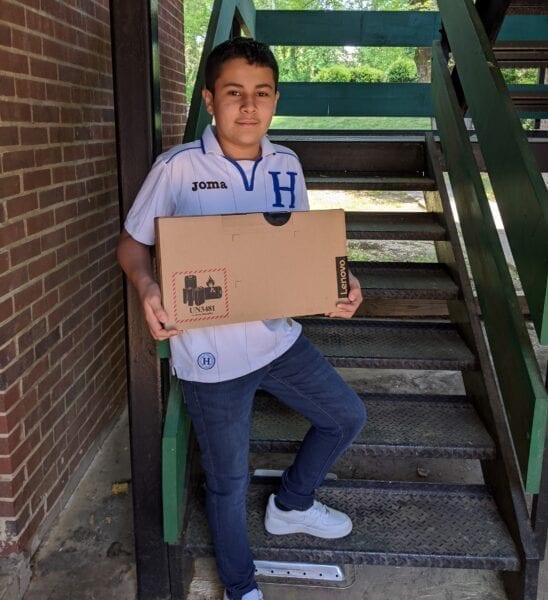 USCRI student receiving donated Lenovo PC for distance learning