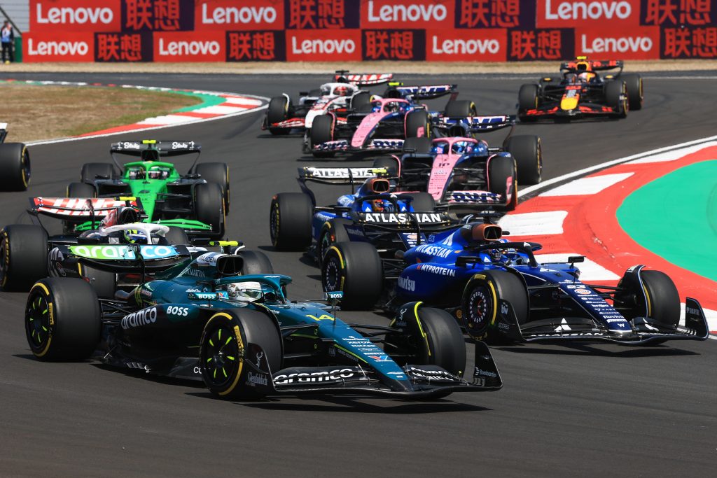 Formula 1 cars racing on a track in China with Lenovo branding behind.