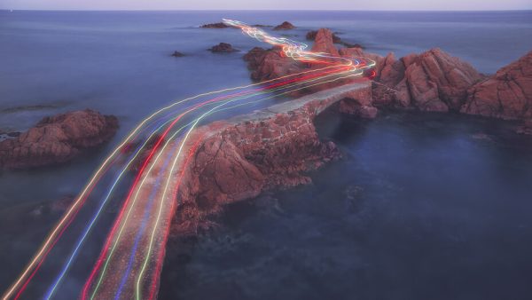 Beams of light travelling over rocky islands in the ocean.