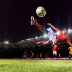 Football player kicking a ball on the pitch -- Lenovo logos in background