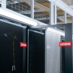 Ser racks in a datacenter - one door is open, each of them labeled with a Lenovo logo.
