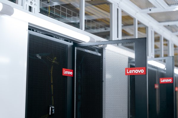 Ser racks in a datacenter - one door is open, each of them labeled with a Lenovo logo.