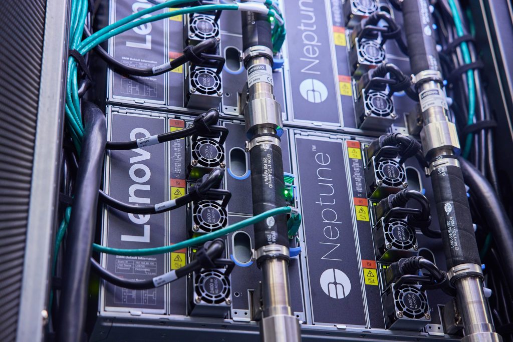 The back of a server stack with Lenovo Neptune branding on it, and cables running from it to the side. 
