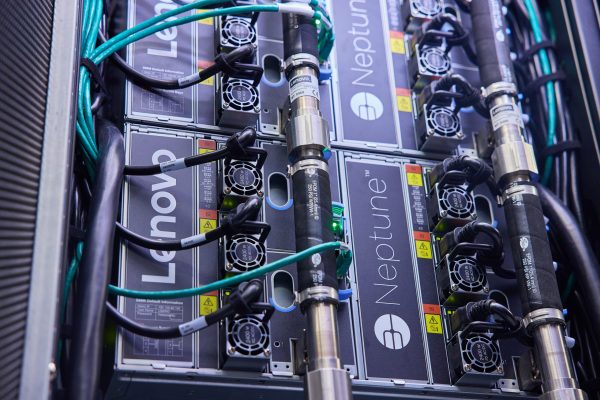 The back of a server stack with Lenovo Neptune branding on it, and cables running from it to the side.