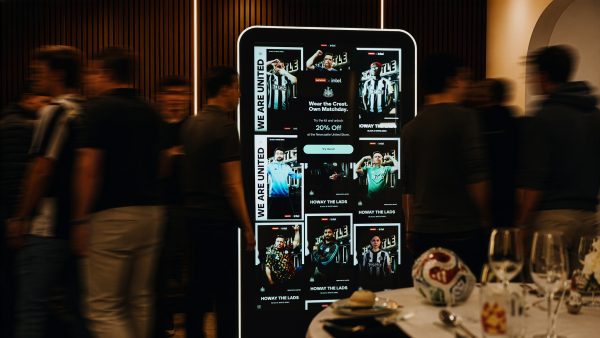 Interactive digital display board surrounded by people and a table